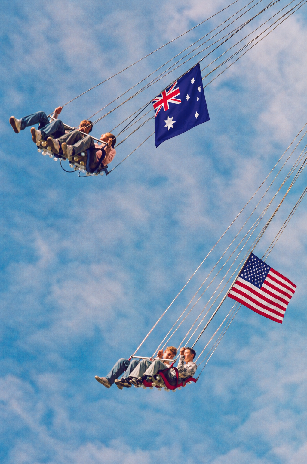 A swing ride with blue sky in the background with Aus and US flags
